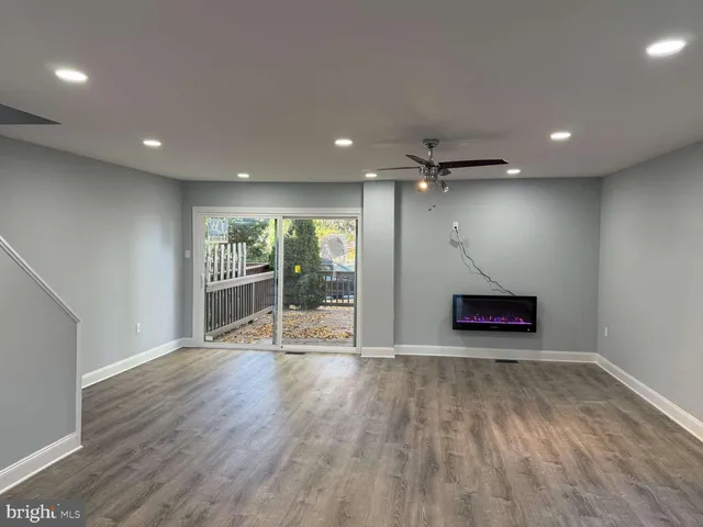 an empty room with wooden floor and a ceiling fan