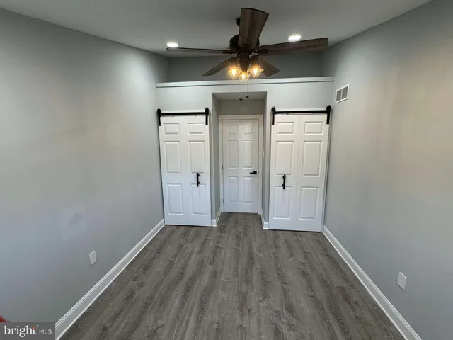 an empty room with wooden floor and a ceiling fan
