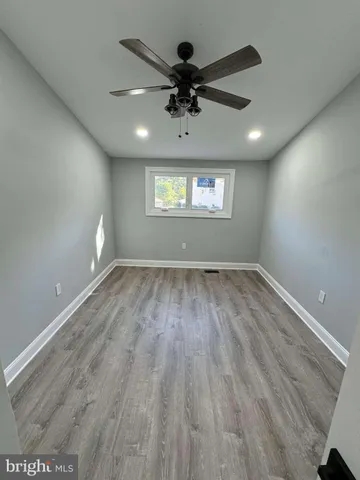 an empty room with wooden floor chandelier fan and windows
