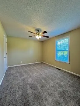 an empty room with a window and chandelier fan