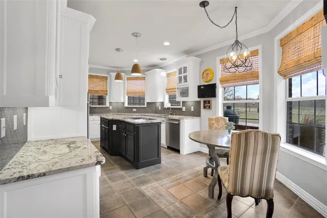 a kitchen with stainless steel appliances granite countertop a stove a sink dishwasher a dining table and chairs with wooden floor