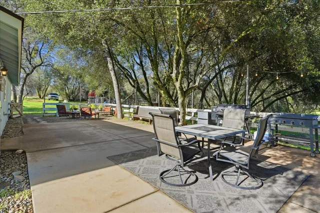 a view of a patio with table and chairs and couches with wooden floor and fence