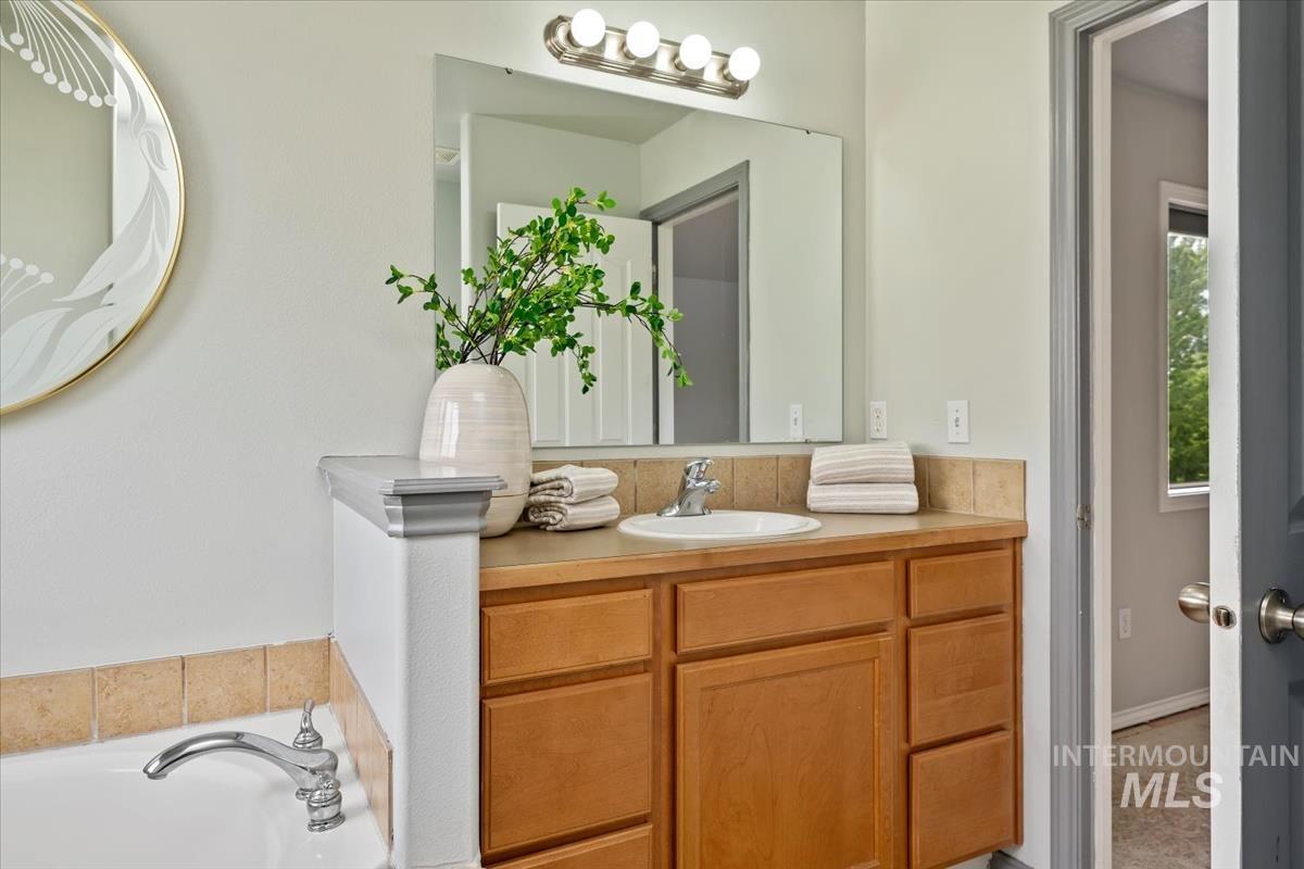 80 Cobblestone Court Middleton, ID 83644 - Photo 22 of 48 Bathroom featuring a wood-finish vanity with a built-in sink, a large wall-mounted mirror, and a chrome light fixture