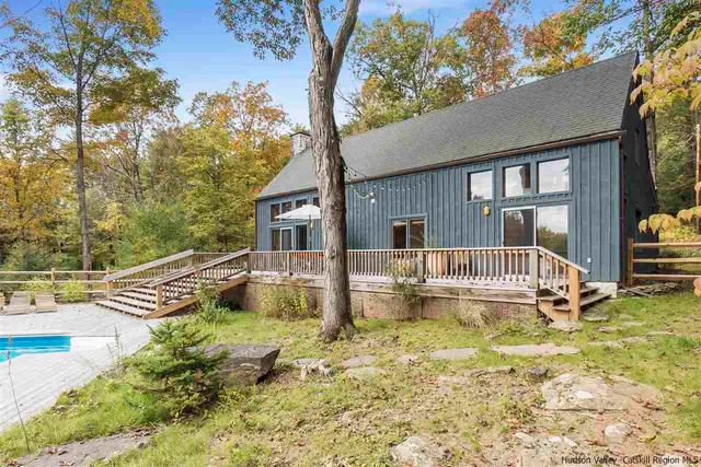 a house view with swimming pool and trees in the background