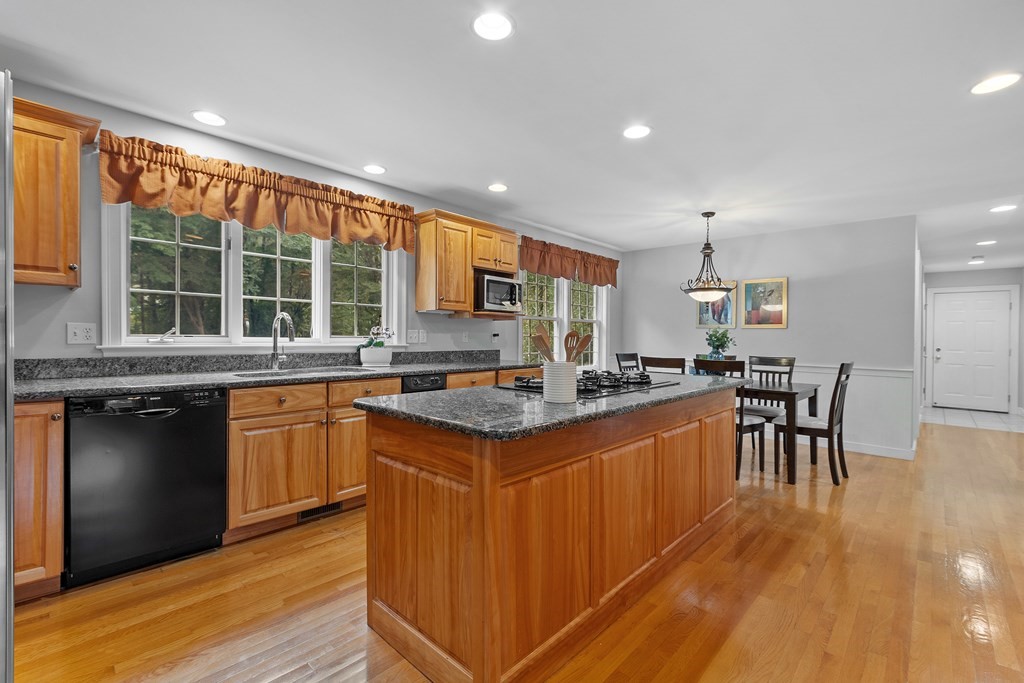298 Old Harvard Road Boxborough, MA 01719 - Photo 10 of 42 a kitchen with stainless steel appliances granite countertop a stove top oven a sink dishwasher a dining table and chairs with wooden floor