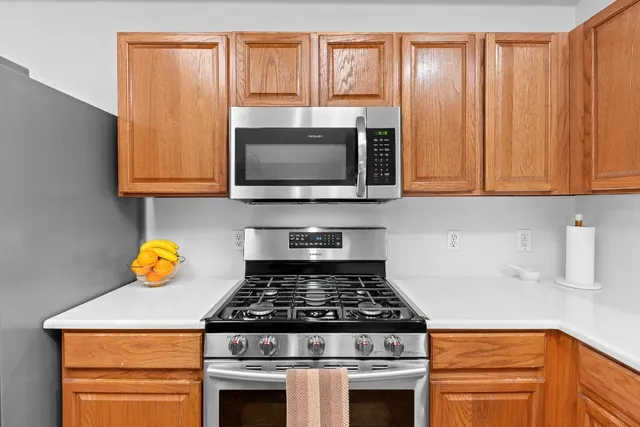 a kitchen with granite countertop wood cabinets stainless steel appliances and a sink