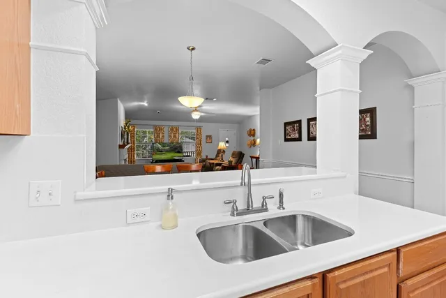 a kitchen with a sink a counter top space and living room view