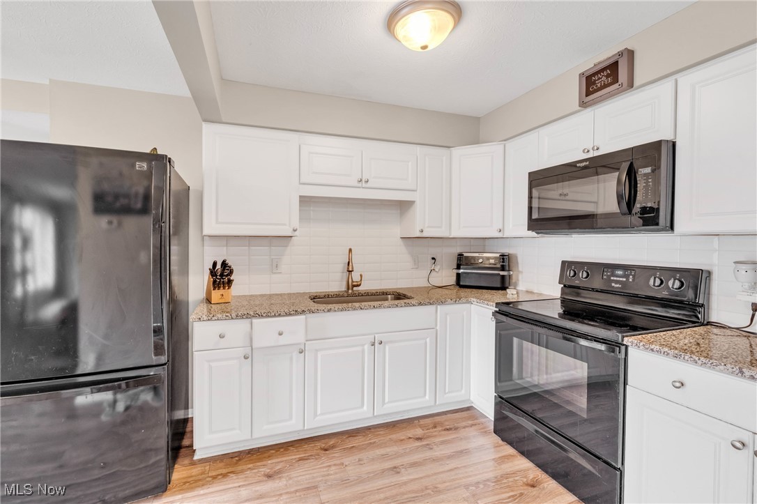 6486 State Road, Unit C5 Parma, OH 44134 - Photo 10 of 27 Kitchen with black appliances, light stone countertops, white cabinets, decorative backsplash, and light wood-style floors