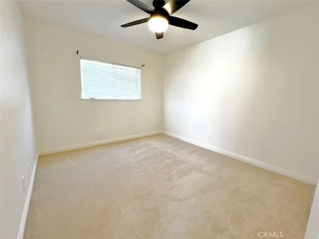 an empty room with a window and a fan