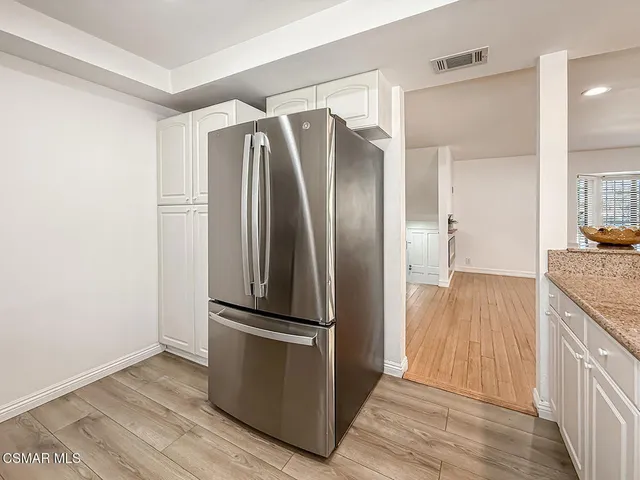 a kitchen with a refrigerator and a wooden floor