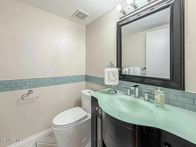 a bathroom with a granite countertop sink a toilet and a mirror