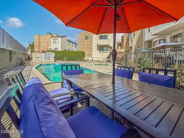 a view of a patio with a table and chairs under an umbrella