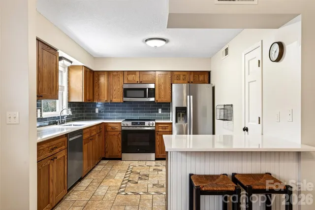 a kitchen with stainless steel appliances granite countertop a refrigerator stove top oven a sink and dishwasher
