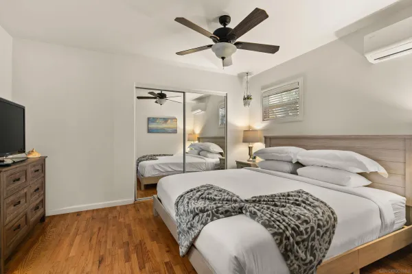 a bedroom with a large bed and a flat tv screen on dresser