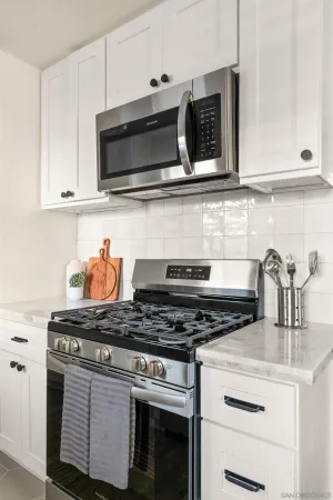 a kitchen with stainless steel appliances granite countertop white cabinets a stove a sink and dishwasher