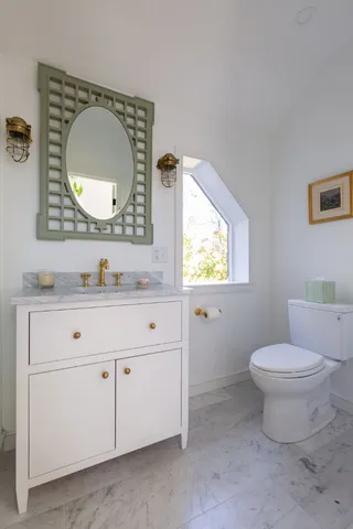 a bathroom with a toilet sink vanity and mirror