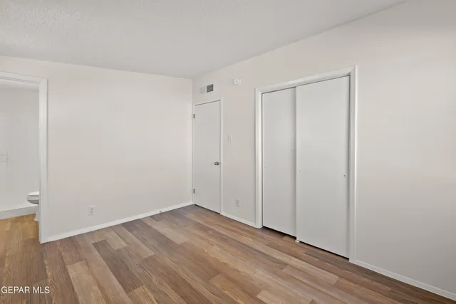 a view of an empty room with wooden floor and closet