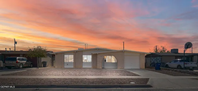 a front view of a house with cars parked