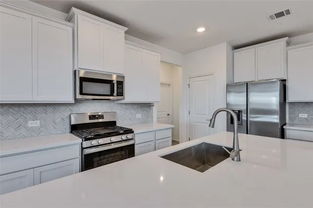 a kitchen with stainless steel appliances a microwave a sink a stove and cabinets