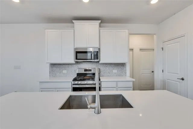 a kitchen with granite countertop white cabinets and stainless steel appliances