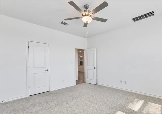 an empty room with a ceiling fan and a window