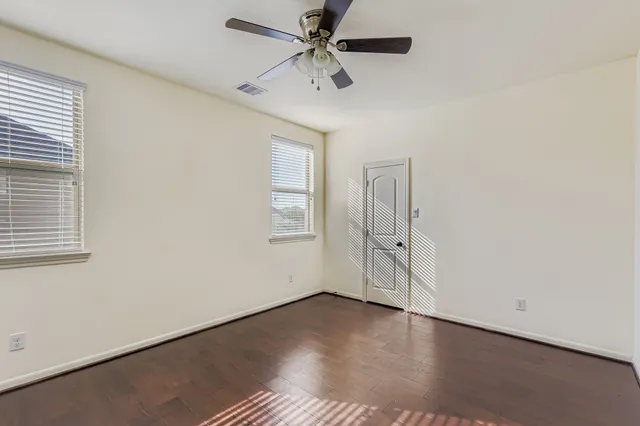 an empty room with windows and fan