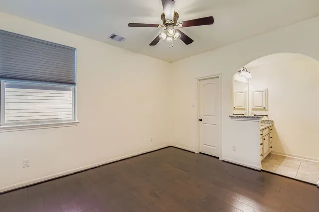 an empty room with a ceiling fan and wooden floor