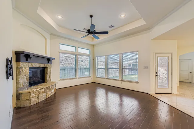 a view of an empty room with wooden floor and a fireplace
