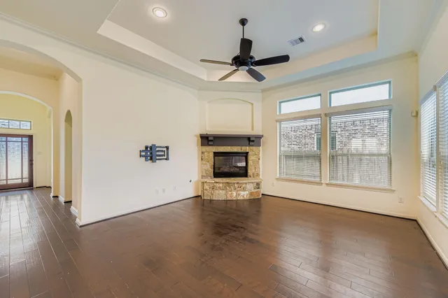 a view of a livingroom with wooden floor a ceiling fan and windows