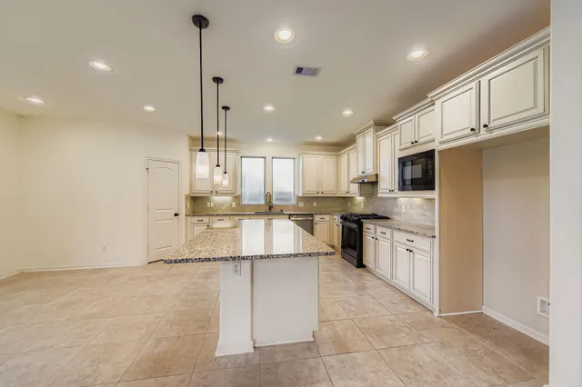 a large kitchen with kitchen island a stove a sink a refrigerator and cabinets