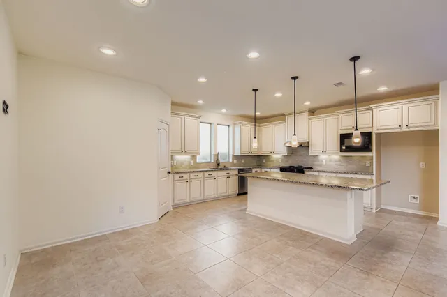 a large kitchen with a large counter top a sink stainless steel appliances and cabinets