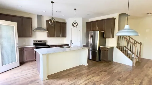 a kitchen with stainless steel appliances granite countertop a refrigerator a stove and a wooden floors