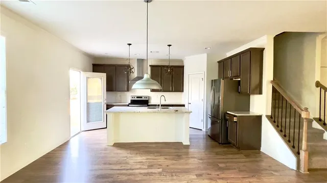 a kitchen with a refrigerator a sink and wooden floor
