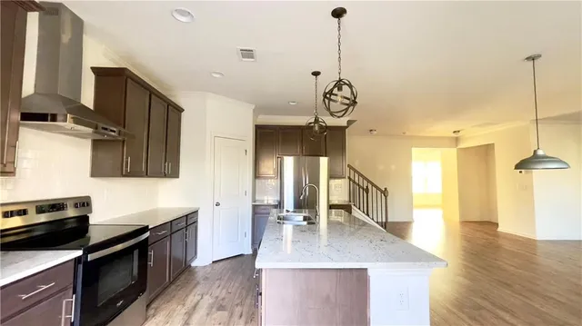 a kitchen with stainless steel appliances granite countertop a sink a stove and a wooden floors