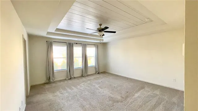 an empty room with a ceiling fan and windows