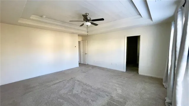 an empty room with a ceiling fan and carpet