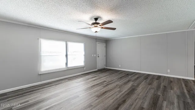 an empty room with wooden floor ceiling fan and windows