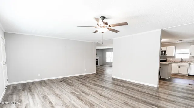 a view of a livingroom with wooden floor and a ceiling fan