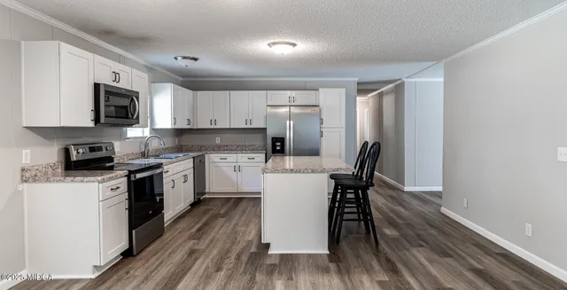 a kitchen with a table chairs a sink dishwasher a stove and a microwave oven with cabinets