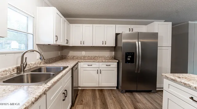 a kitchen with granite countertop a refrigerator sink and cabinets