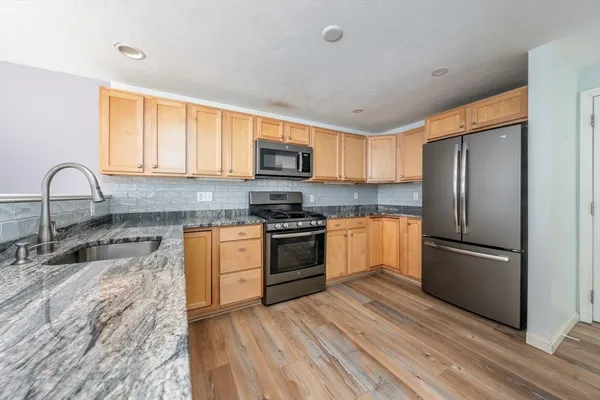 a kitchen with granite countertop a refrigerator stove and sink