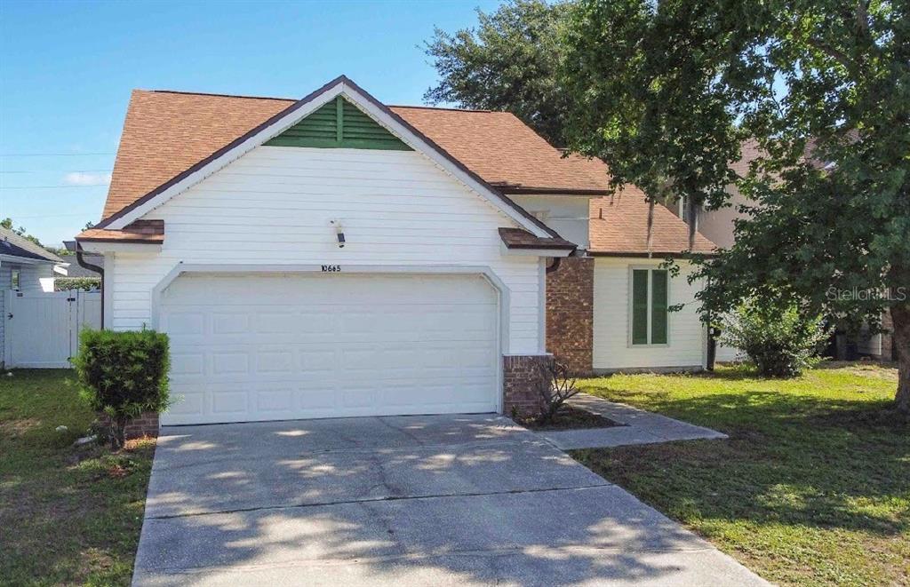 10665 Huntridge Road Orlando, FL 32825 - Photo 2 of 12 a front view of house with yard and trees in the background
