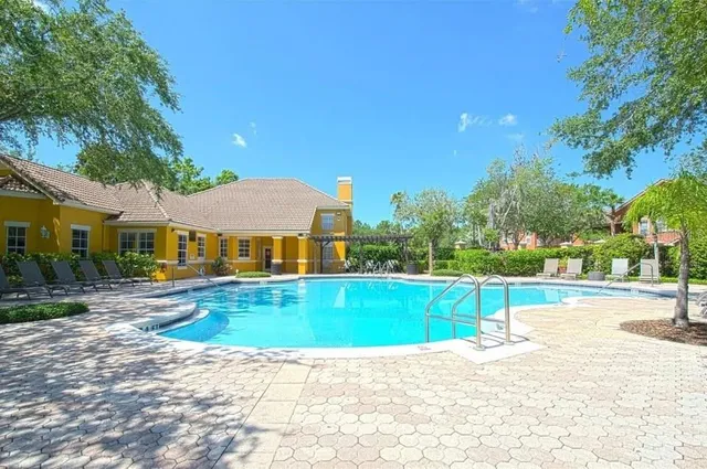 a view of pool with lawn chairs and plants