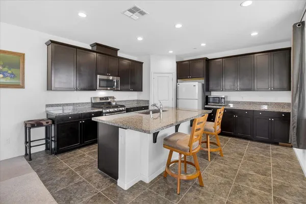 a kitchen with stainless steel appliances granite countertop a stove top oven a sink and a refrigerator