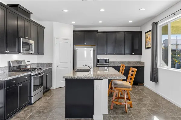 a kitchen with stainless steel appliances kitchen island granite countertop a refrigerator and a stove top oven
