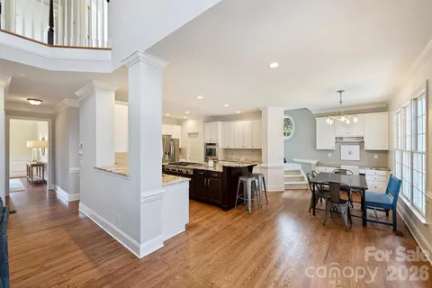 a kitchen with a dining table chairs wooden floor appliances and cabinets
