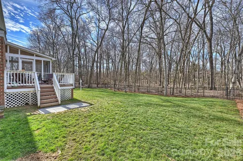 a view of a backyard with wooden fence and a large tree