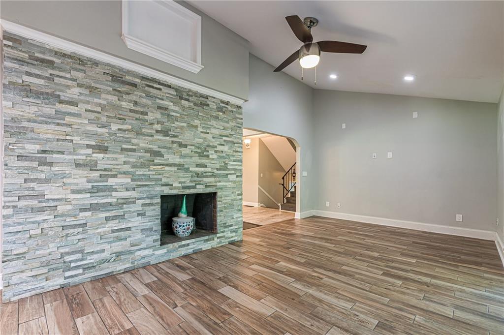 1574 Old Spring House Lane Atlanta, GA 30338 - Photo 21 of 55 an empty room with wooden floor a ceiling fan a fireplace and windows