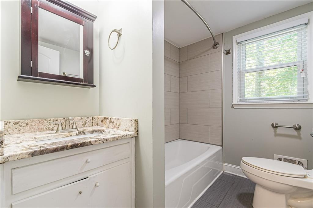 1574 Old Spring House Lane Atlanta, GA 30338 - Photo 40 of 55 a bathroom with a granite countertop sink a toilet a mirror and bathtub