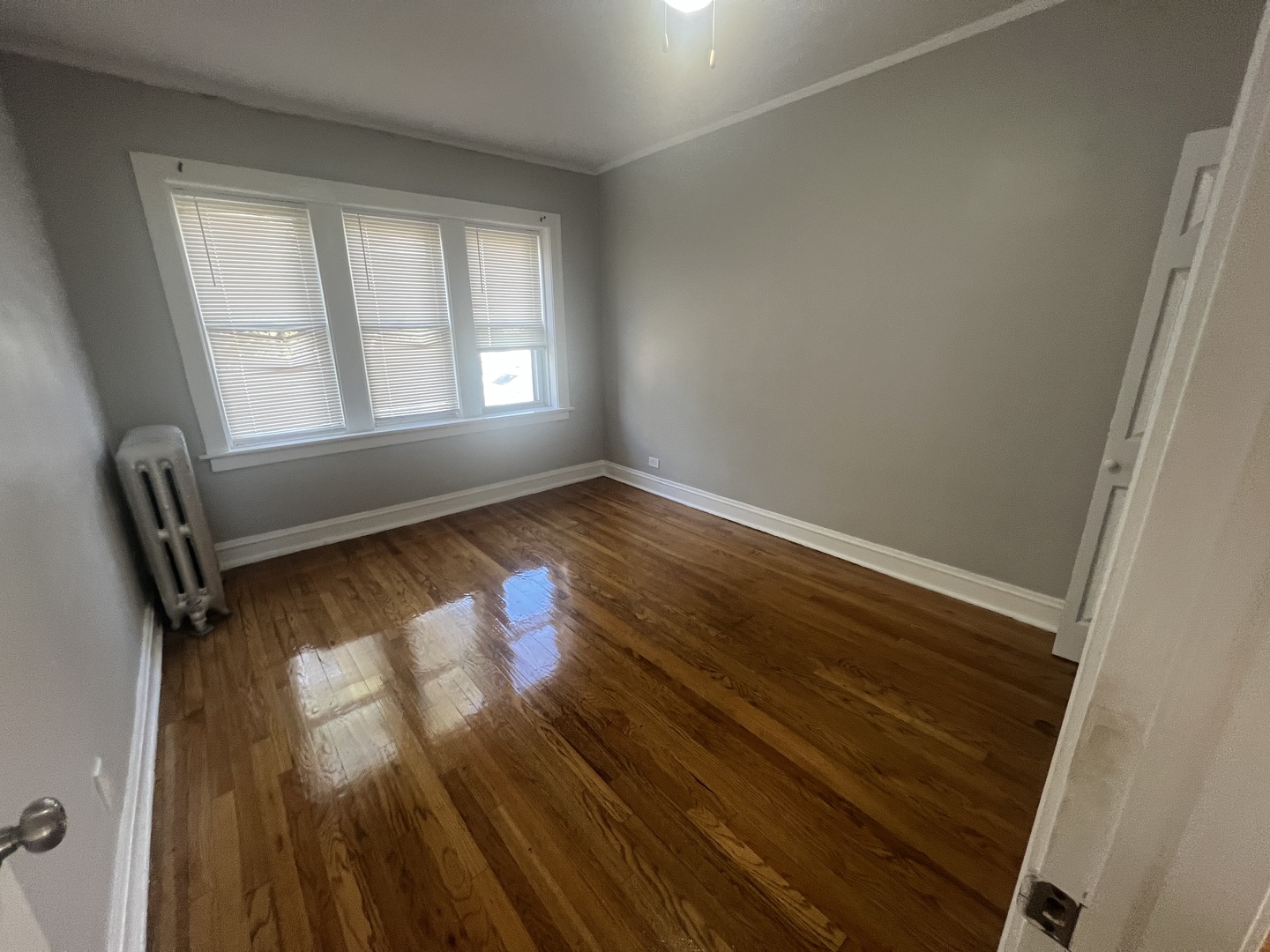 243 East 108th Street, Unit 2 Chicago, IL 60628 - Photo 5 of 8 an empty room with wooden floor and windows